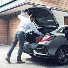 Homme ouvrant le coffre à l'arrière de la Honda Civic 5 Portes