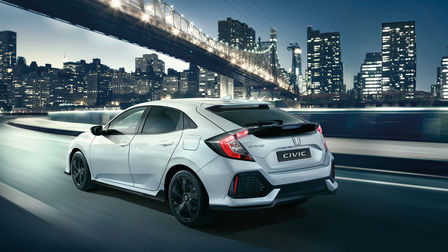 Vue de trois quarts arrière de la Honda Civic Black Edition, roulant dans un paysage urbain.
