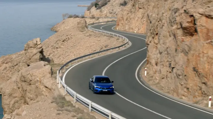 Honda Civic Hybrid driving down coastal road.
