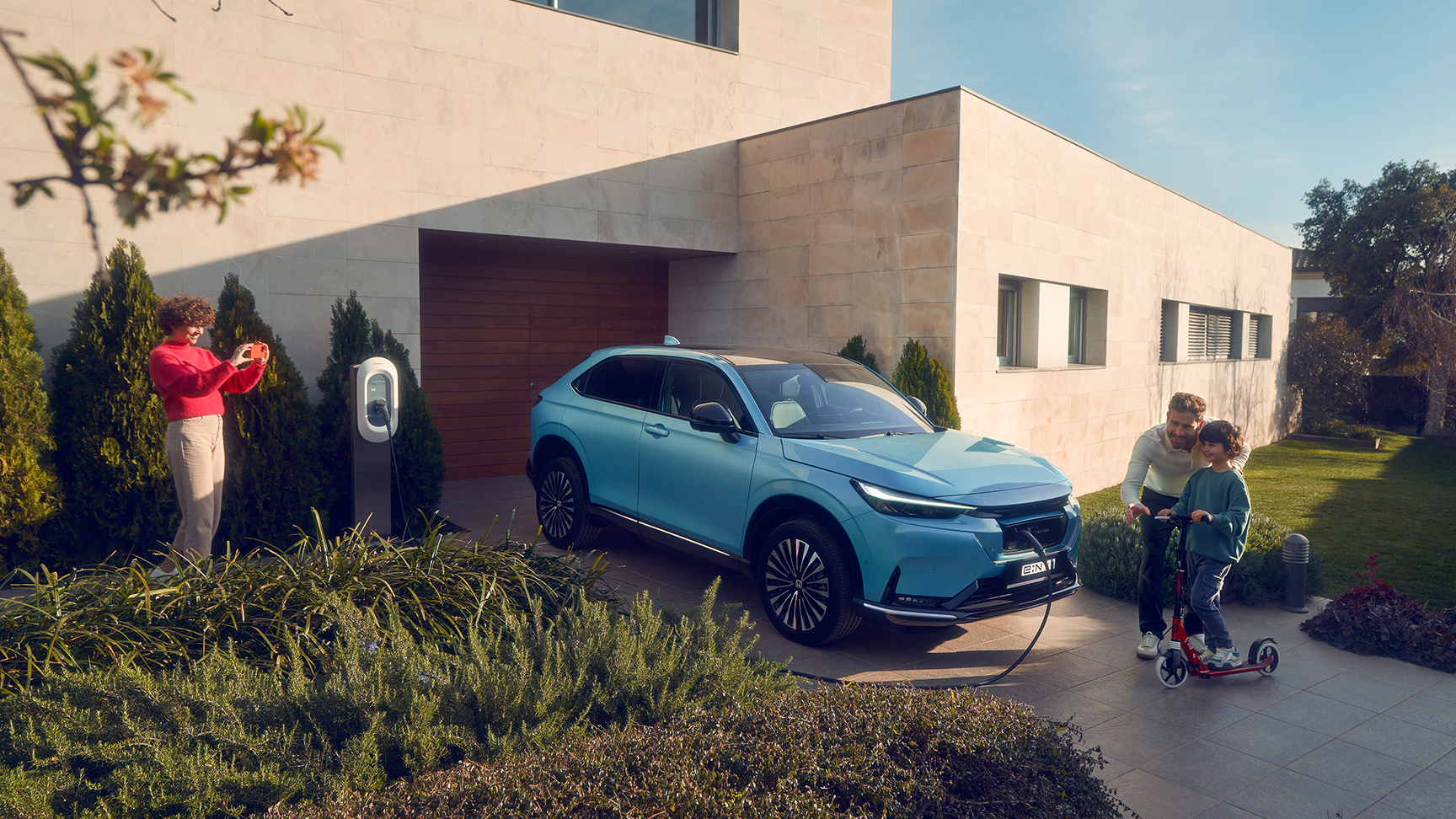 Famille jouant dans une allée à côté du Honda e:Ny1 en cours de recharge.