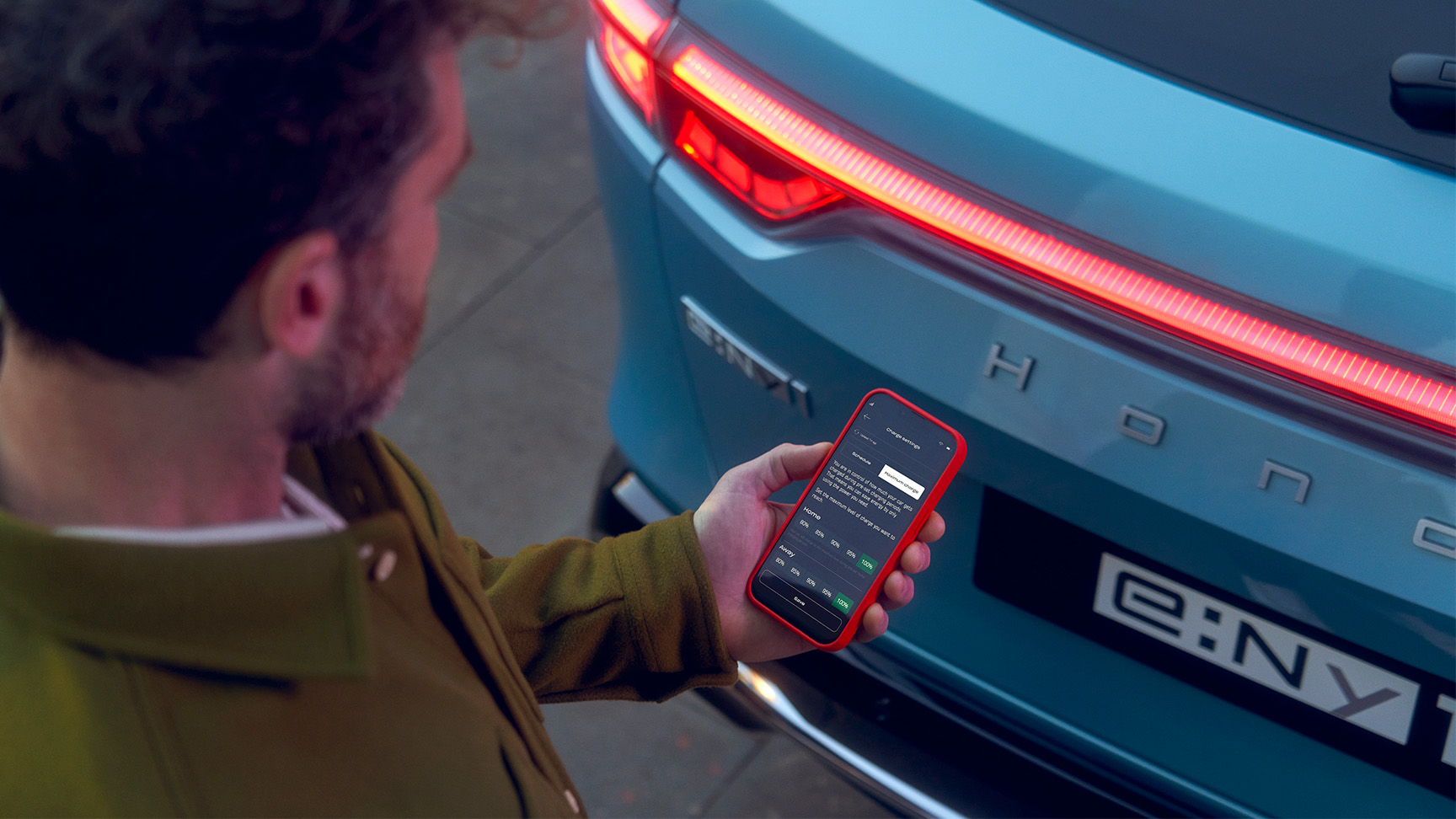 Homme regardant l’application My Honda Plus à côté du Honda e:Ny1
