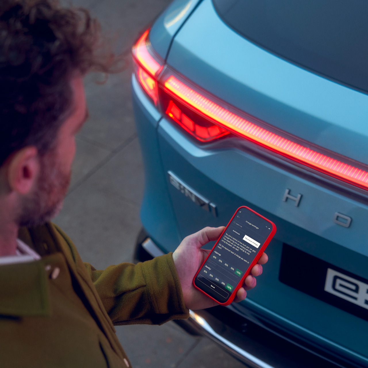 Homme regardant l’application My Honda Plus à côté du Honda e:Ny1