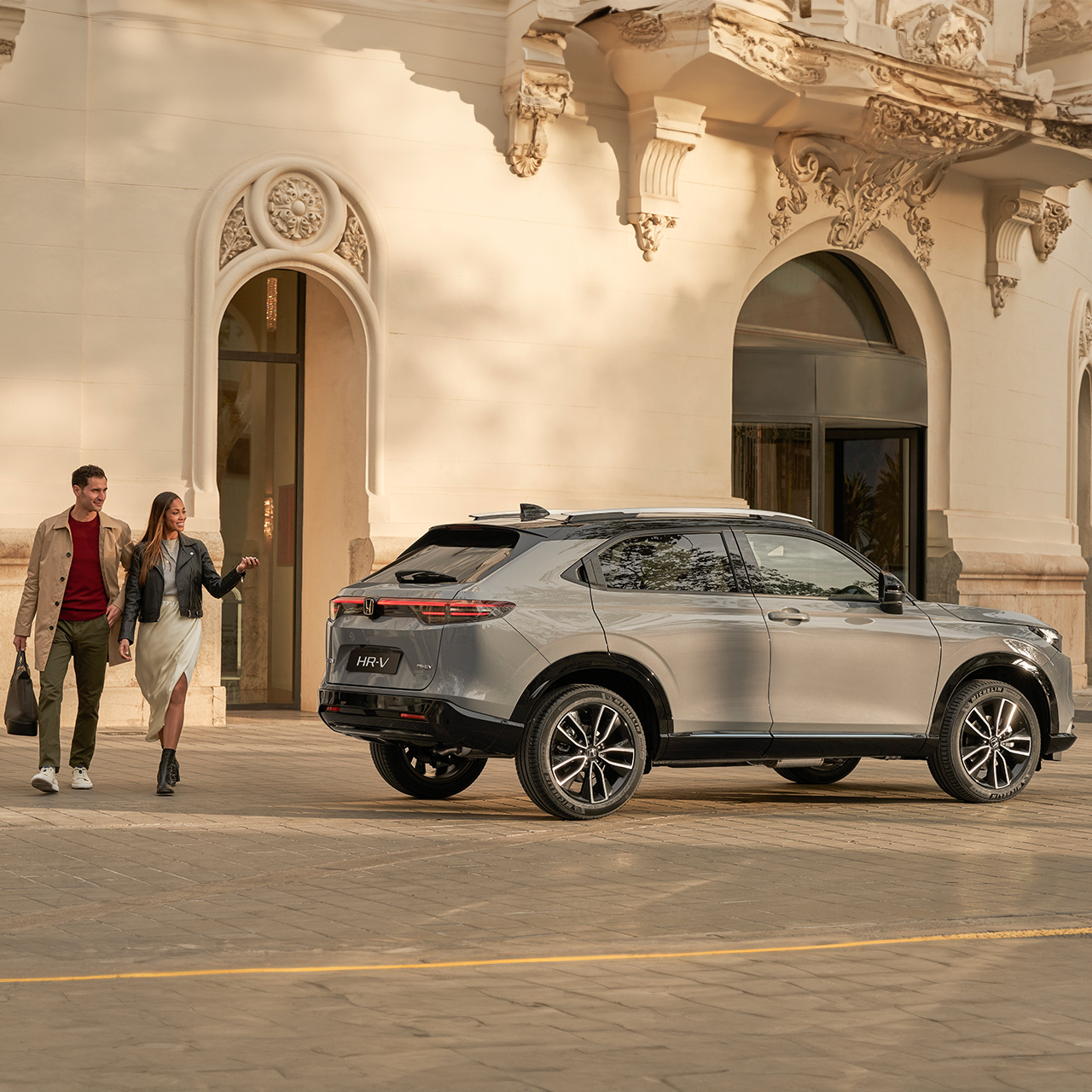 Vue latérale du Honda HR-V à l'extérieur d'un hôtel, avec un couple qui passe.