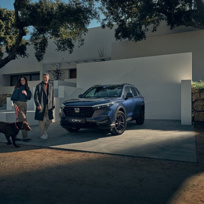 Couple promenant un chien à côté d'un Honda CR-V garé.