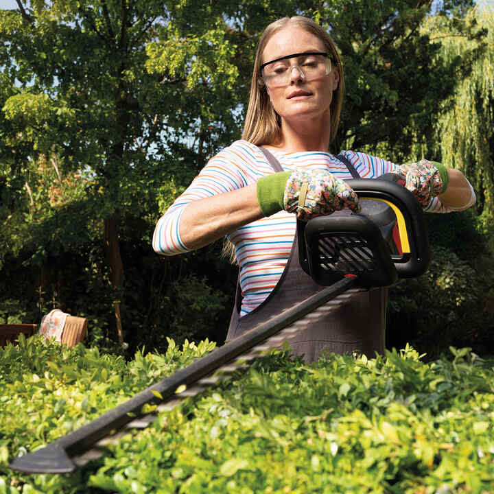 Femme utilisant un taille-haie dans un jardin