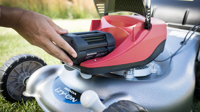 Close up of lawn mower with model changing the battery.