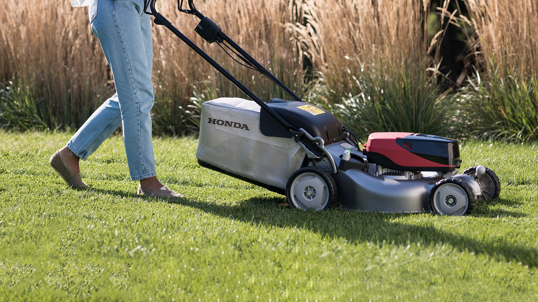 Femme poussant la tondeuse à gazon IZY-ON.