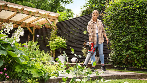 Femme utilisant un souffleur sans fil dans le jardin