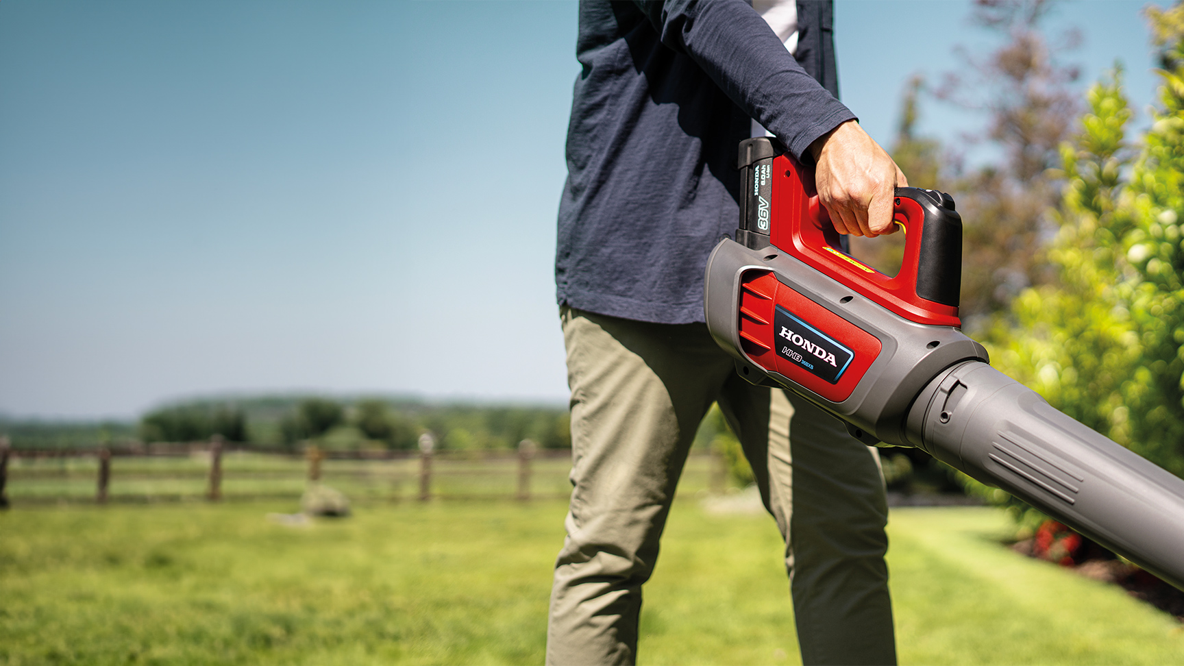 Homme utilisant un souffleur de feuilles sans fil dans un jardin.