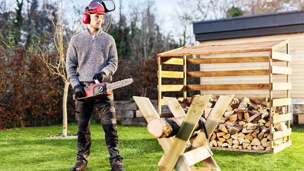 Homme dans un jardin utilisant une tronçonneuse sans fil.