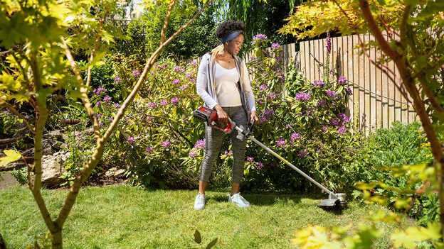 Femme utilisant le coupe-bordure sans fil Honda dans un jardin.