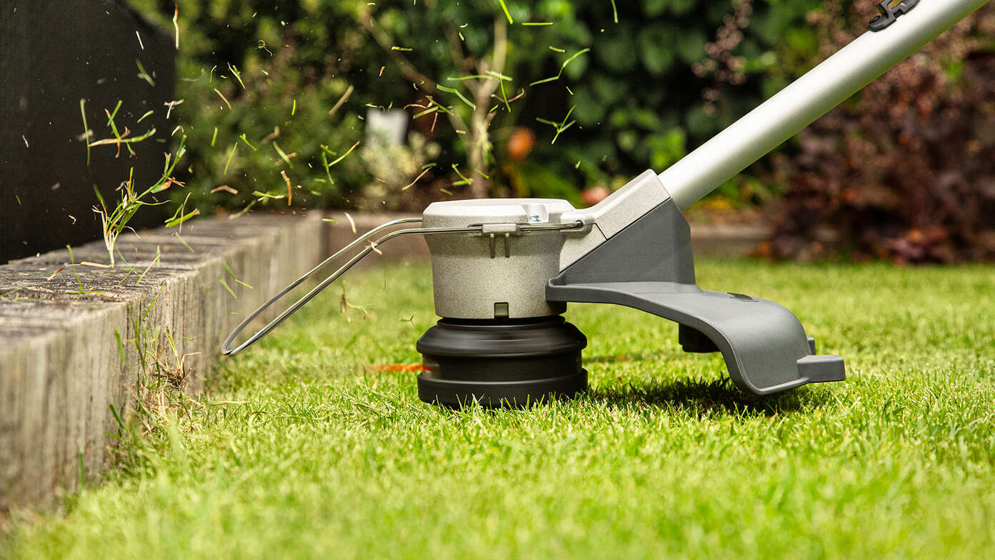 Coupe-bordure sans fil Honda en train d'égaliser le bord de la pelouse d’un jardin.
