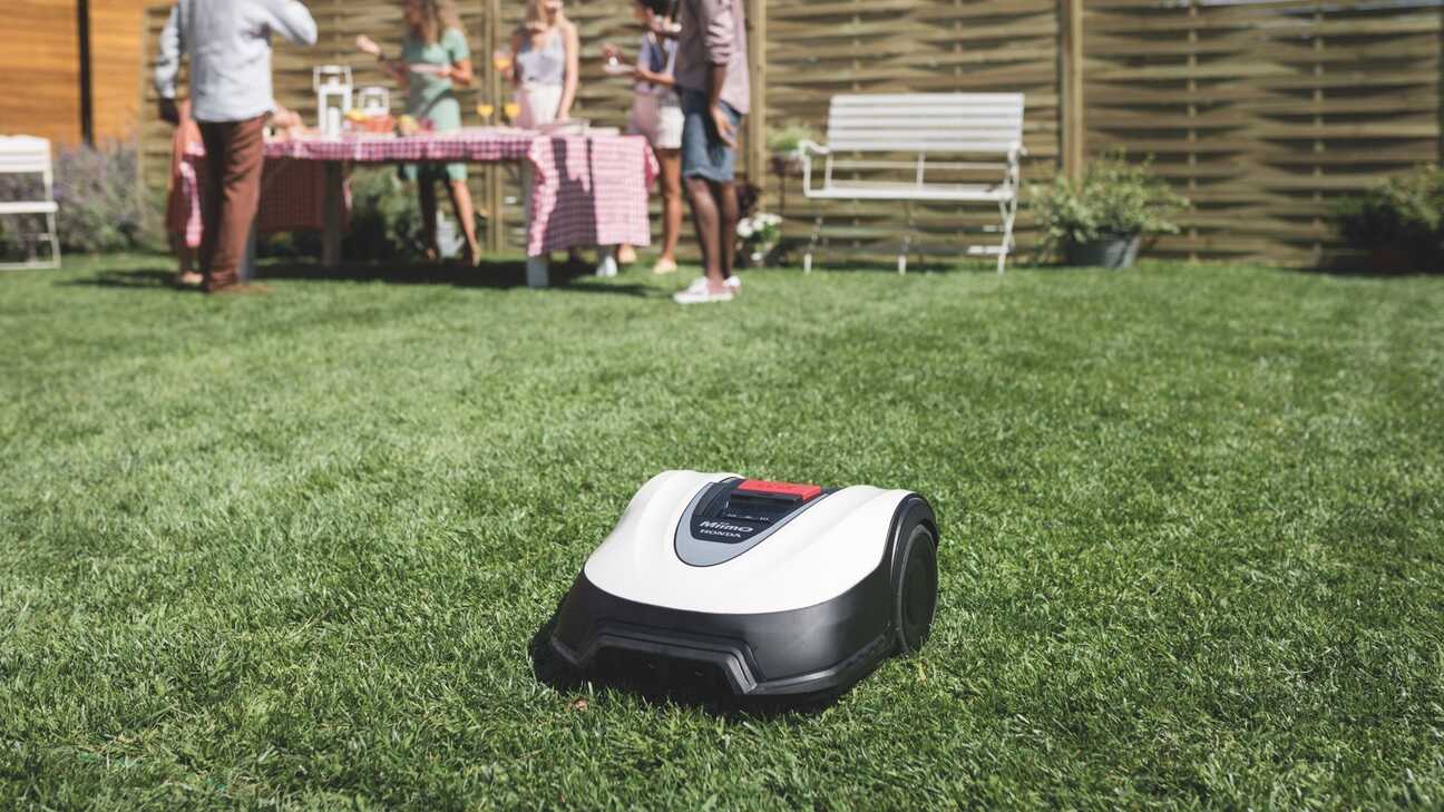 Vue de trois quarts avant de la Honda Miimo dans un jardin avec des mannequins et des meubles en arrière-plan.