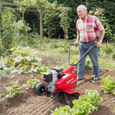 Motobineuse compacte, utilisée par un démonstrateur, dans un jardin.