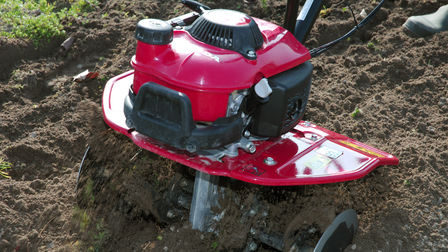 Gros plan d'une motobineuse utilisée dans un jardin.