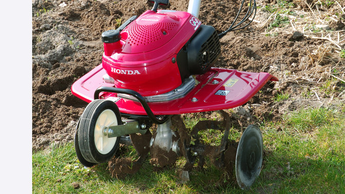 Gros plan de la motobineuse, dans un jardin.
