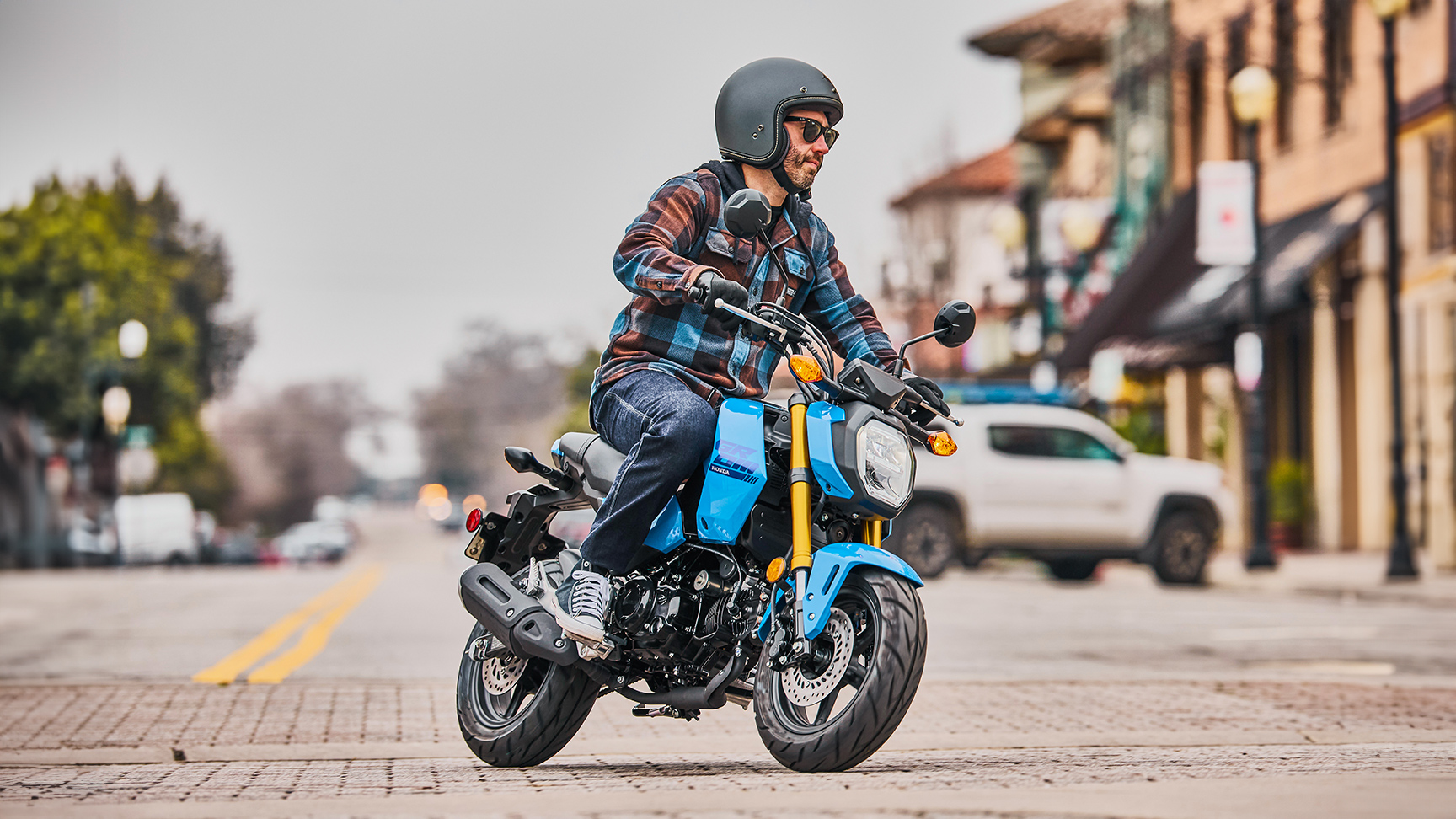 MSX125 Grom bleu sur route, avec pilote à l’entrée d’un virage 
