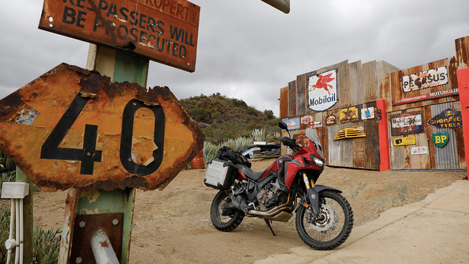 Honda CRF1000L Africa Twin stationné devant une station-service au bord de la route.