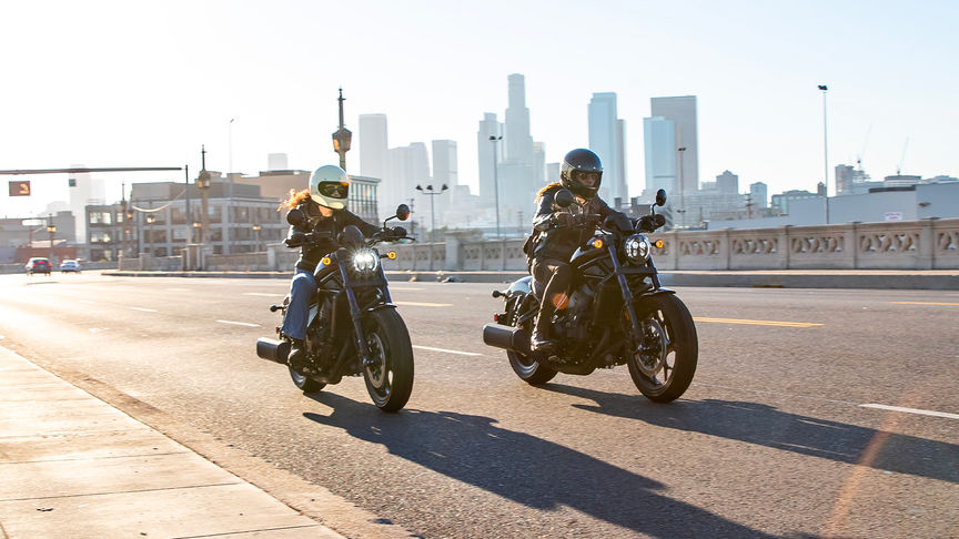 Vue de trois quarts avant droit de deux Honda CMX1100 Rebel avec motards en ville urbain en plein jour