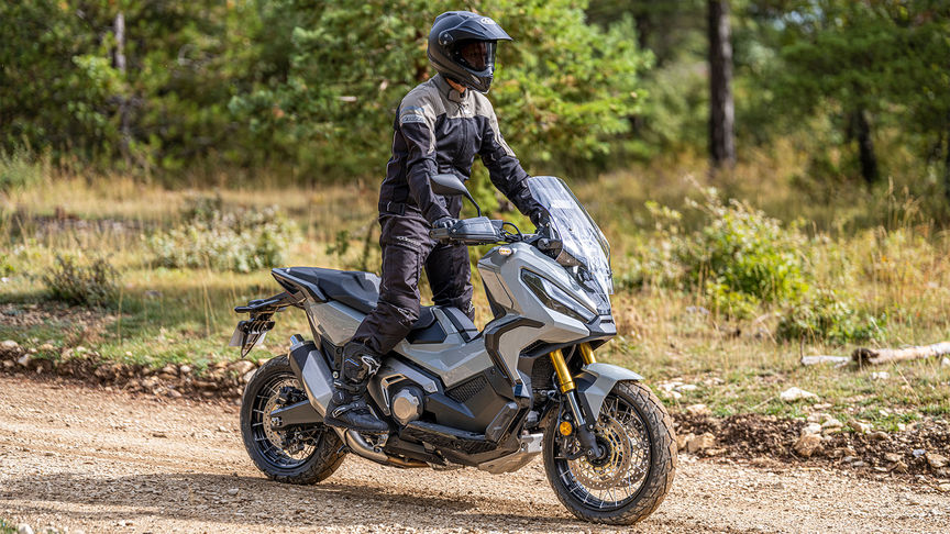 Côté droit de la Honda X-ADV en gris avec motard sur une piste de terre