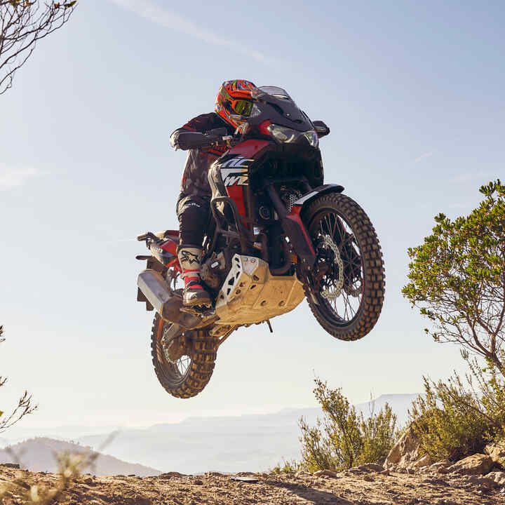 Pilote au guidon d'une moto Honda CRF1100L Africa Twin roulant sur un terrain accidenté