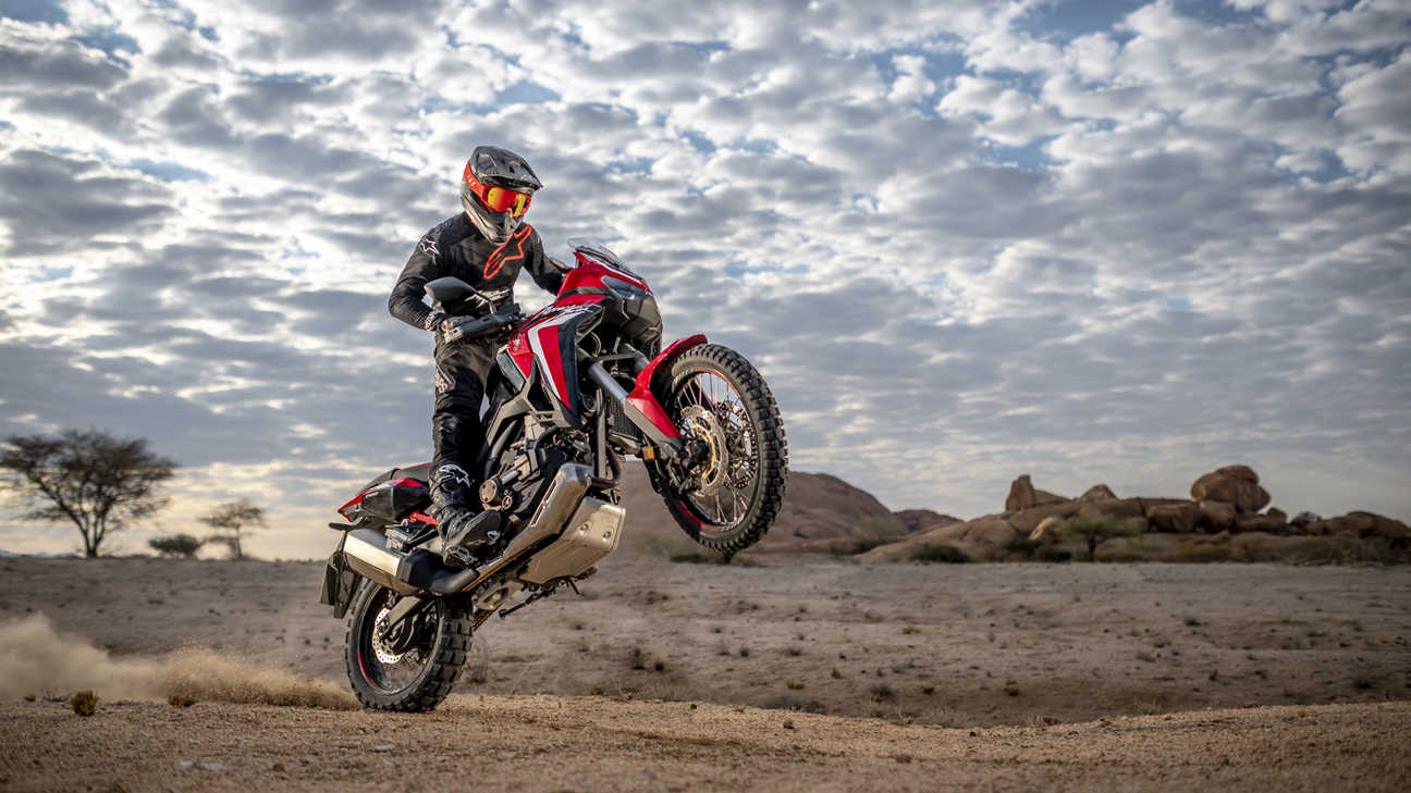 Honda Africa Twin, vue de trois quarts avant droit, sur sa roue arrière dans un paysage désertique