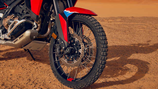 Gros plan sur les roues d’une moto CRF1100L Africa Twin dans un environnement désertique.