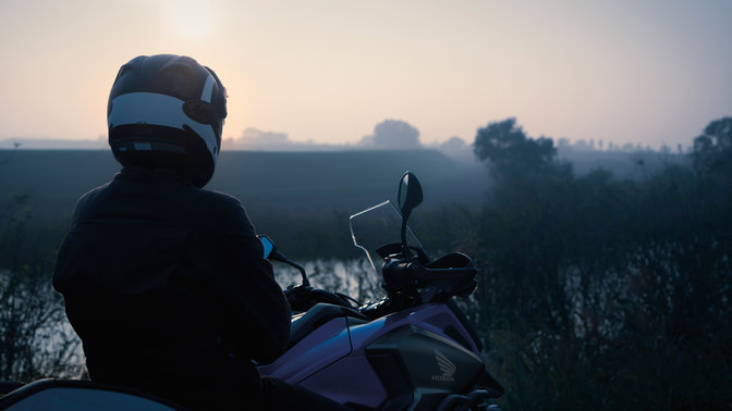 Pilote assis sur la Honda NC750X, garée à la campagne.