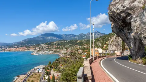 Route panoramique sous un ciel bleu le long du littoral méditerranéen à la frontière franco-italienne.