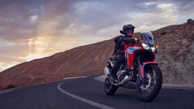 Vue de trois quarts avant de l’Africa Twin avec motard sur route