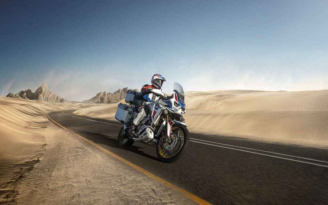 Honda Africa Twin Adventure sports, vue de trois quarts avant droit, pilotée sur une route dans un paysage désertique