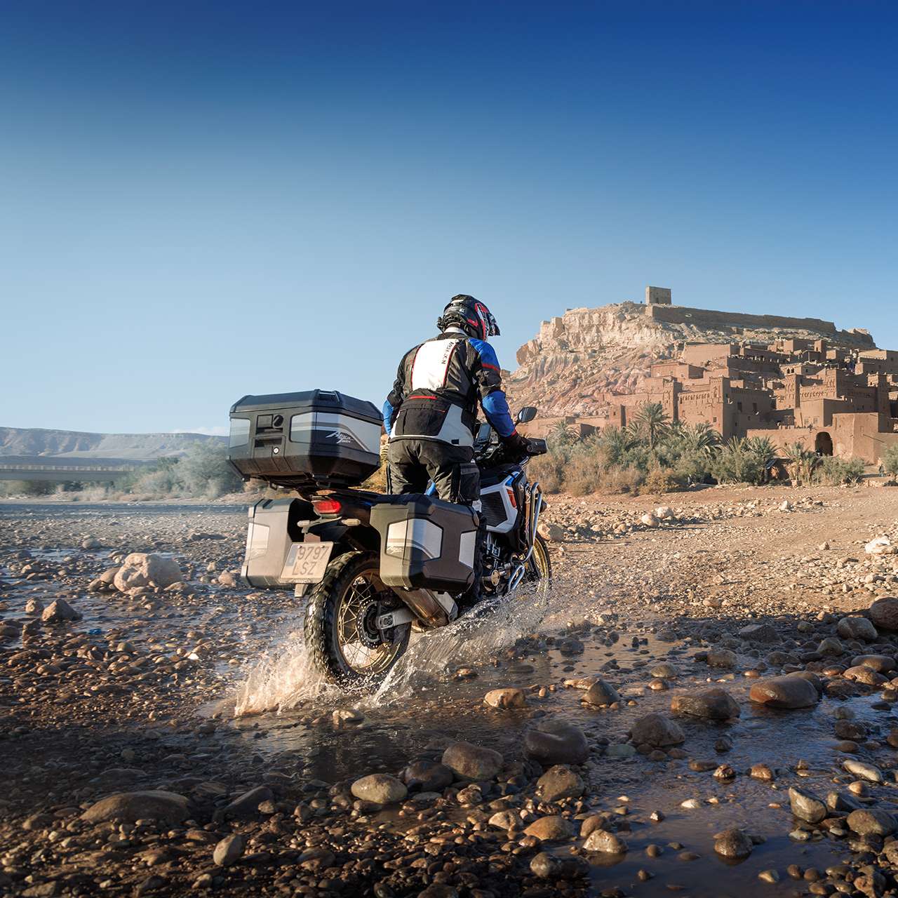Motard sur CRF1100 ATAS dos à la route avec accessoires de randonnée.