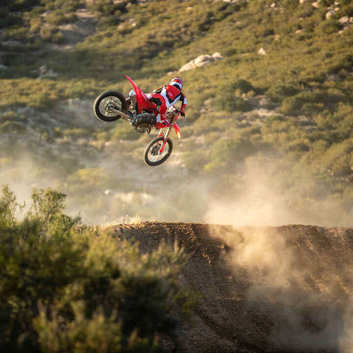 Honda CRF250R faisant un saut dans un environnement tout-terrain