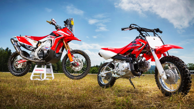 Vue de trois quarts latérale de la CRF50F, stationnée dans un champ. Vue de face