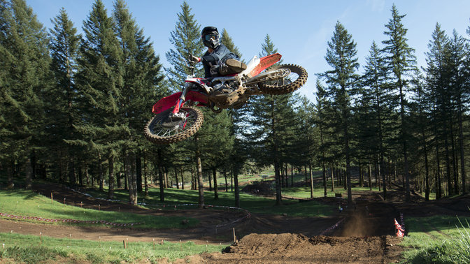 CRF450R avec pilote en plein saut. Sur chemin de terre.