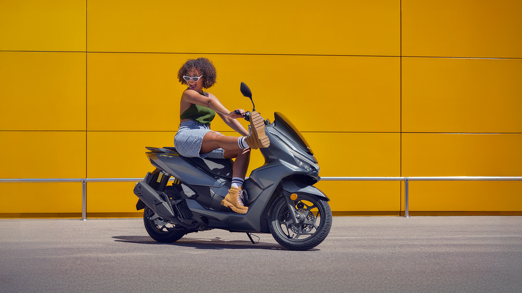 Une personne assise sur la moto PCX 125.