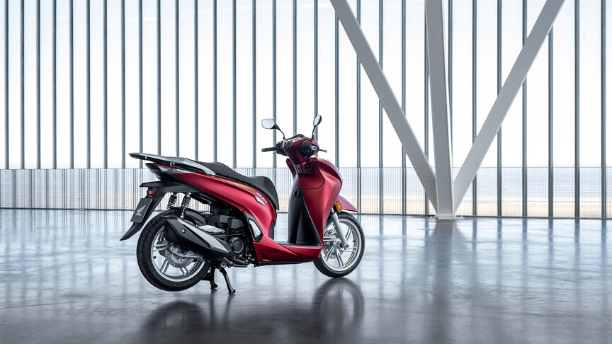 Vue de trois-quart avant droit du Honda SH350i, rouge, avec pilote, sur la route