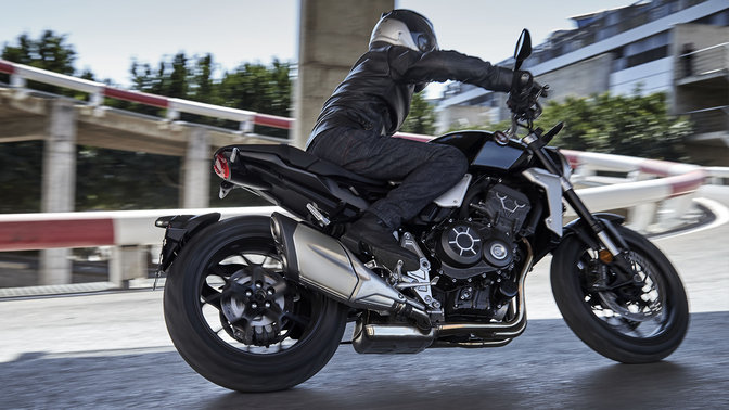 Vue de trois quarts avant de la Honda Neo Sports Caf&eacute; CB1000R, entrep&ocirc;t en arri&egrave;re-plan.