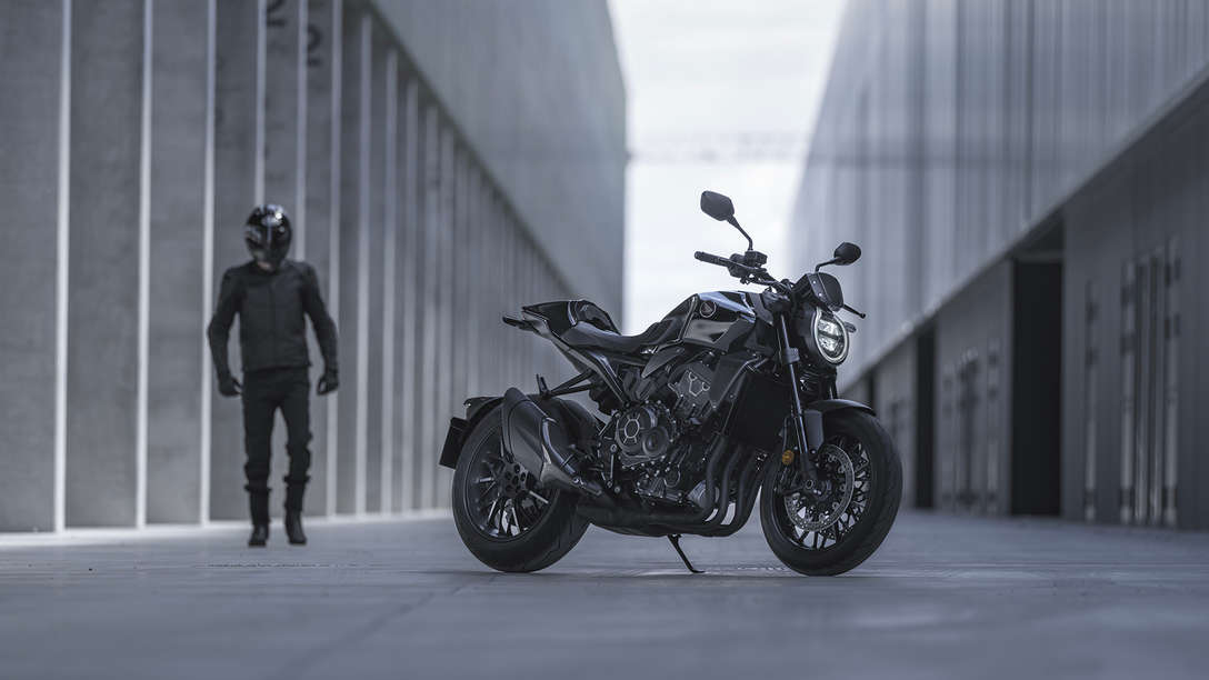 Roadster Honda CB1000R Black Edition - homme se tenant &agrave; c&ocirc;t&eacute; de la moto dans la rue entre deux b&acirc;timents