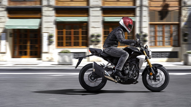 Plan latéral de la Honda CB300R Neo Sports Café conduite sur une route.