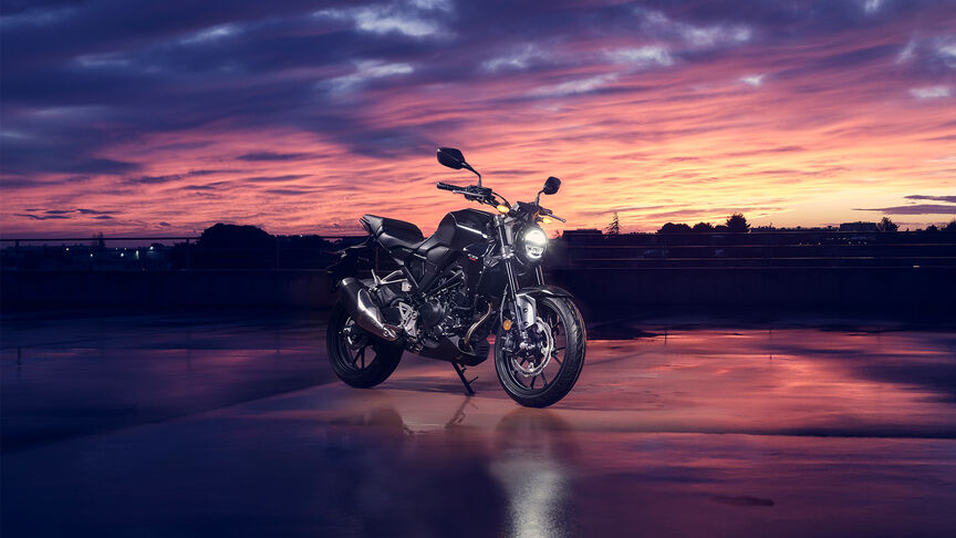 Vue de trois quarts avant de la Honda CB300R contemplée par une femme dans un studio.