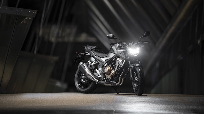 Vue de trois quarts avant droit de la CB500F, la nuit dans un paysage urbain