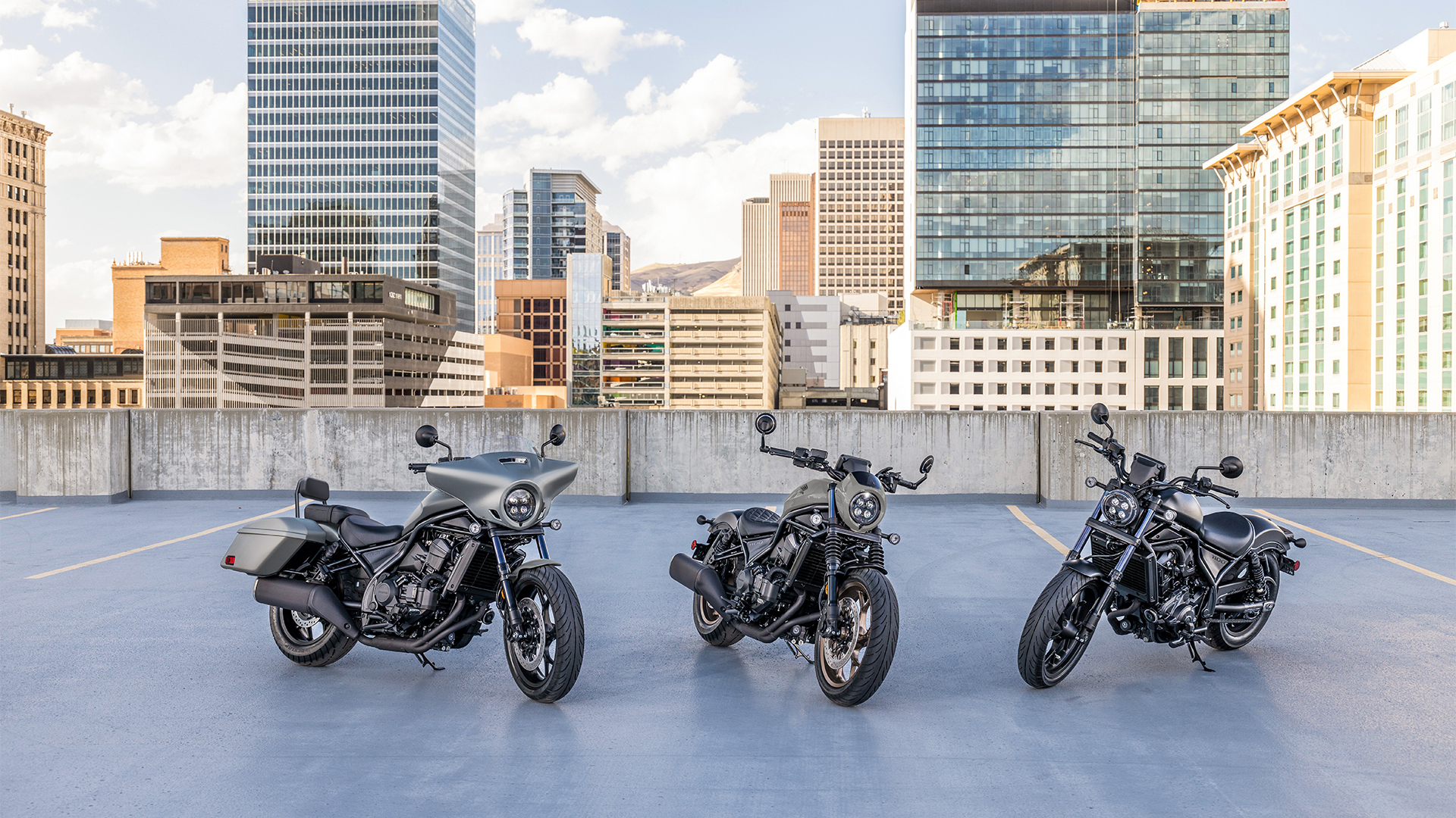 Trois motos CMX1100 à l'extérieur, devant des bâtiments modernes.