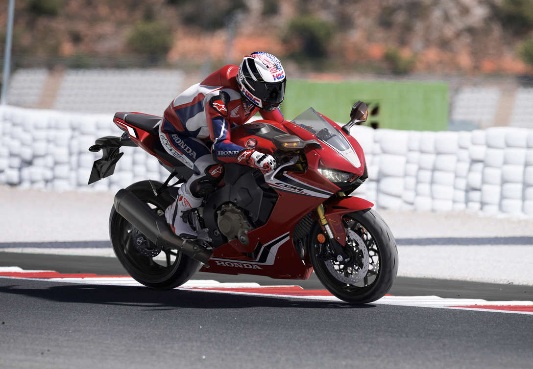 Vue de trois quarts face de la Honda CBR100RR Fireblade avec un pilote sur circuit.