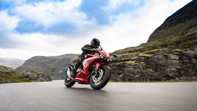 Vue de trois quarts avant droit de la CBR500R, pilot&eacute;e sur une route de montagne