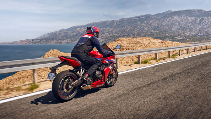 Motard sur une Honda CBR650R vue de derrière sur route. 